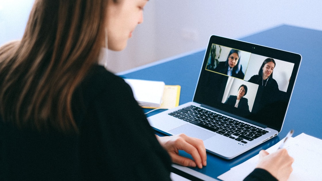 Uma pessoa faz anotações enquanto participa de uma videochamada no notebook.